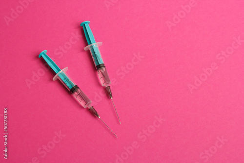 Medical syringe on a pink background. A syringe for injection. The concept of health and beauty
