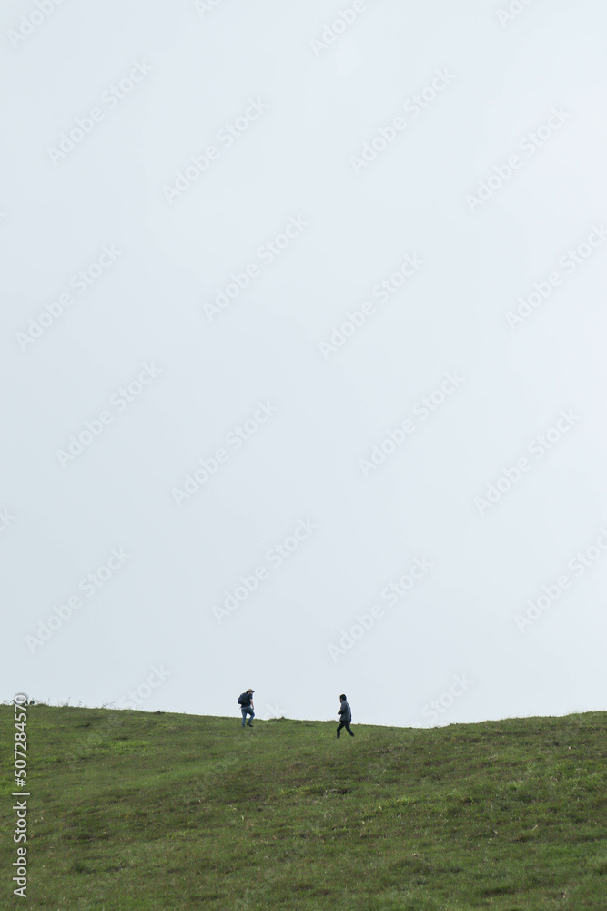 two explorers on the prairie climbing a hill walking in the wilderness looking for mushrooms