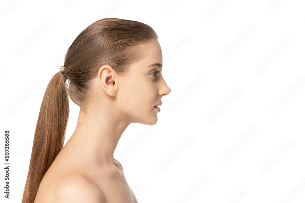 Side view portrait of young beautiful girl with low ponytail posing isolated over white studio background. Clear face Side view portrait of young beautiful girl with low ponytail posing isolated over white studio background. Clear face