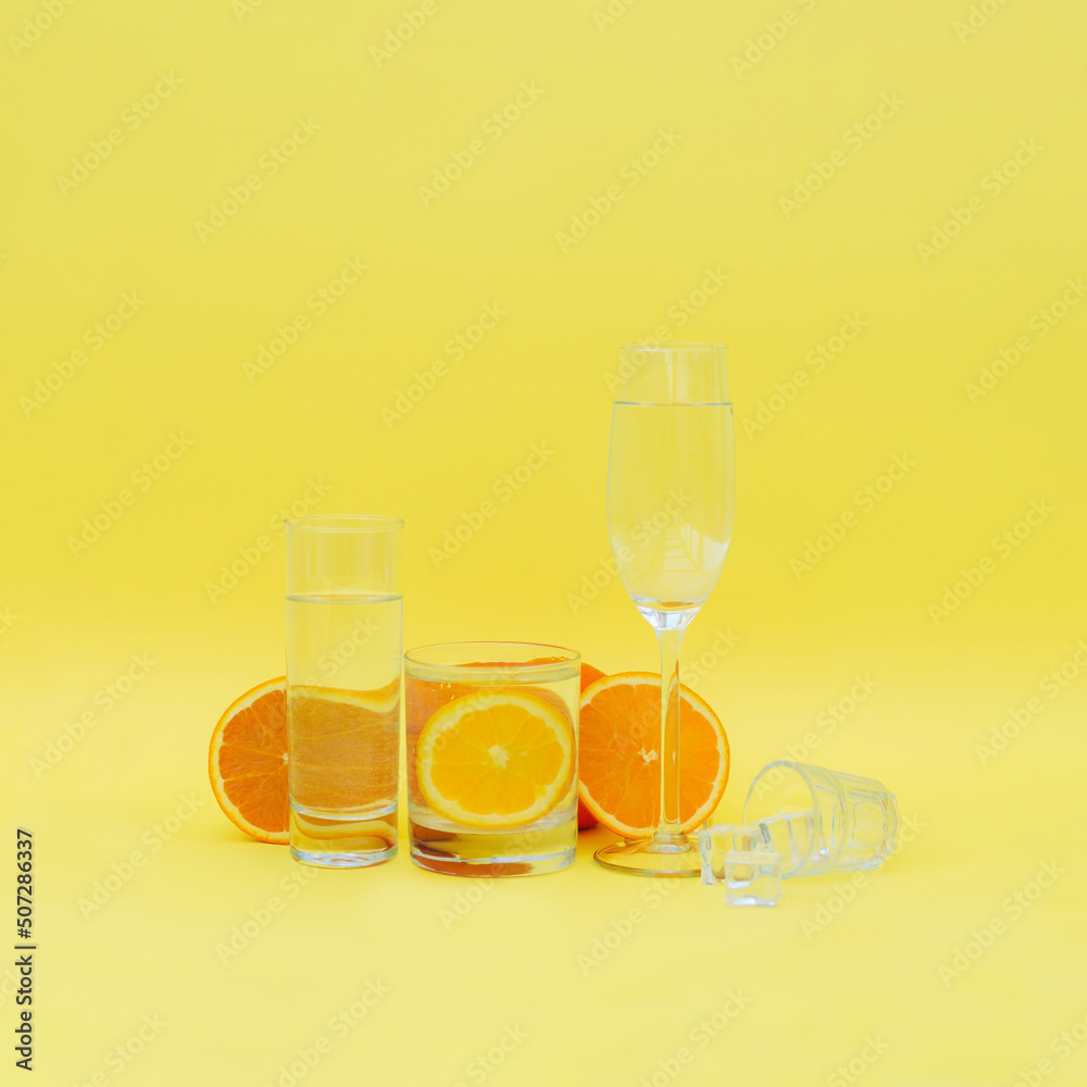 Set - a glass of fresh orange juice. Orange juice with orange slices. Minimal summer concept on yellow background. Water and orange.