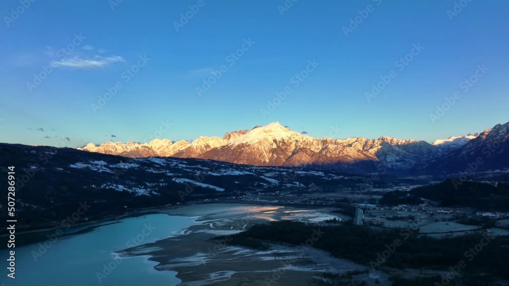 Drone Aerial view of lake and mountains with snow in winter. First lights in the morning make it look like golden hour. Drone Aerial view of lake and mountains with snow in winter. First lights in the morning make it look like golden hour.