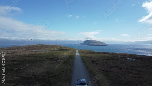 White campervan driving at an scenic road between wind turbines at Feroe Islands photo