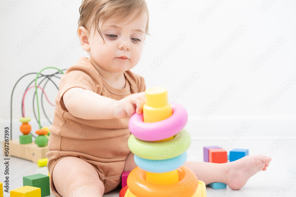 cute baby girl playing with pyramid and wooden toys at home. early children development cute baby girl playing with pyramid and wooden toys at home. early children development