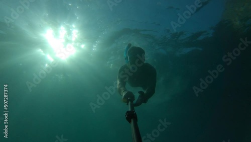 Wallpaper Mural silhouette of a man snorkeling and taking a selfie on a background of bright yellow sun shining from behind. Contrasting rays of the sun under the water illuminating the silhouette of a man immersed Torontodigital.ca