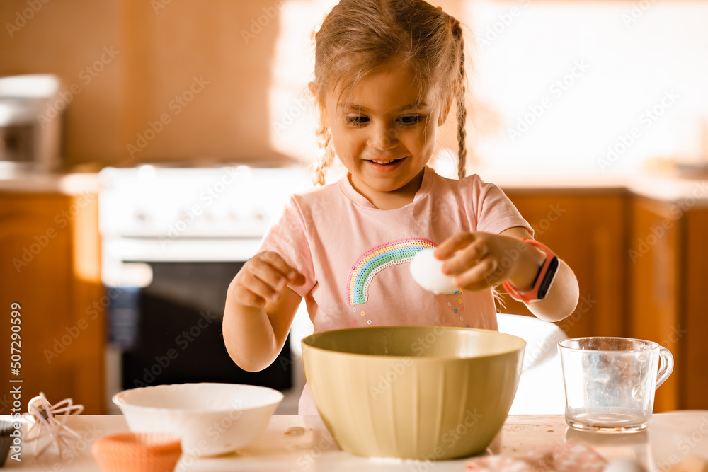 Cute smiling little blonde girl cooking dough in kitchen at home Cute smiling little blonde girl cooking dough in kitchen at home