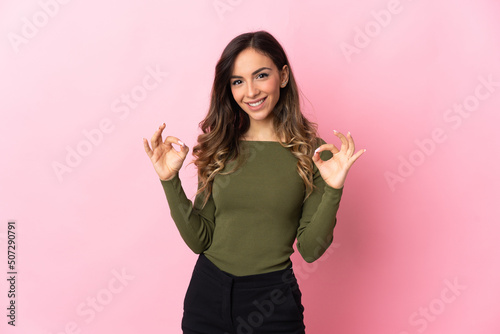 Young caucasian woman isolated on pink background showing ok sign with two hands © luismolinero