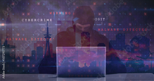 Image of caucasian male hacker and cyber attack warning over cityscape