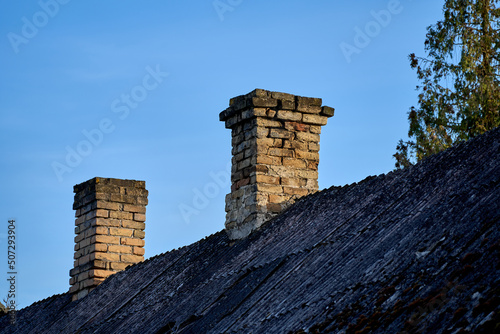 Fotografia An old brick chimney against the blue sky.