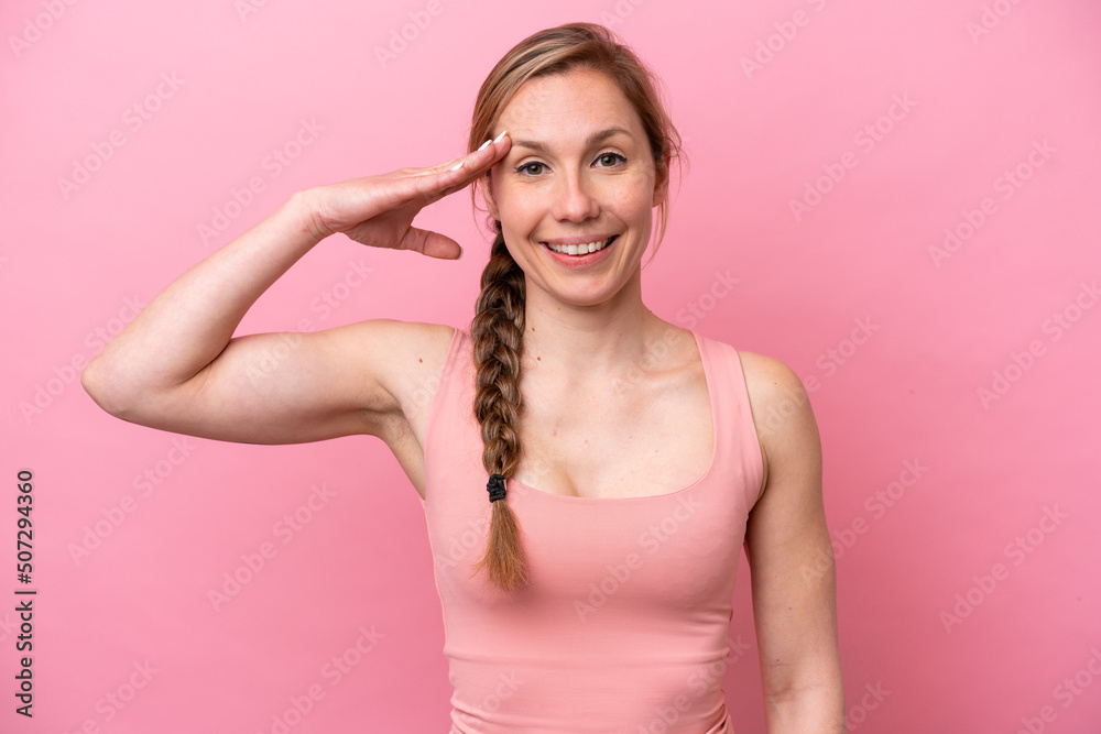 Young caucasian woman isolated on pink background saluting with hand with happy expression Young caucasian woman isolated on pink background saluting with hand with happy expression