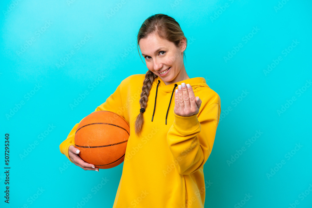 Young caucasian woman isolated on blue background playing basketball and doing coming gesture