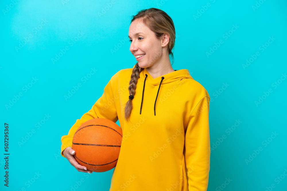 Young caucasian woman isolated on blue background playing basketball