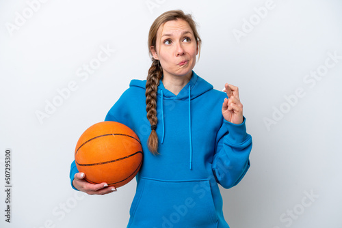 Young caucasian woman playing basketball isolated on white background with fingers crossing and wishing the best
