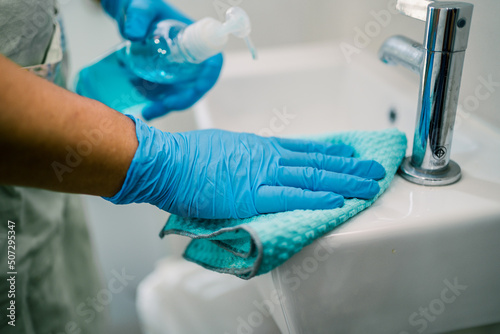 Maid cleaning wash and scrub basin in toilet at home. © amazing studio