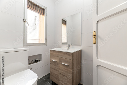 Bathroom with wooden furniture  square frameless mirror  porcelain sink and white painted solid wood door