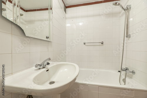 Bathroom with white porcelain sink and small tub with chrome faucets