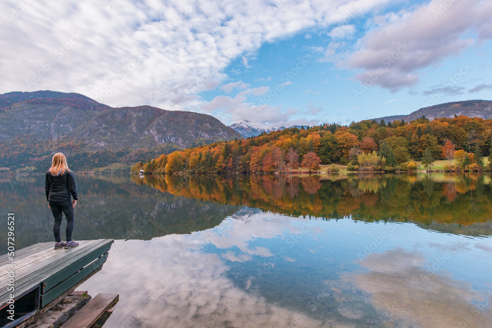 Young female standing on a pier at lake Bohinj in Julian Alps mountain range.