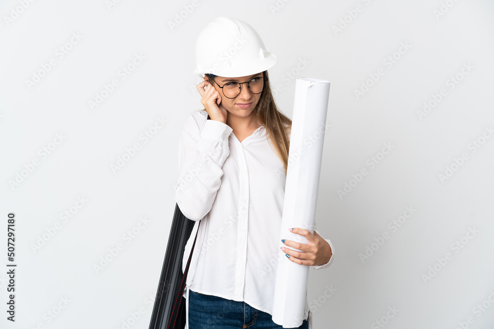 Young Lithuanian architect woman with helmet and holding blueprints isolated on white background frustrated and covering ears Young Lithuanian architect woman with helmet and holding blueprints isolated on white background frustrated and covering ears