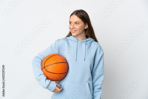 Young Lithuanian woman playing basketball isolated on white background looking side