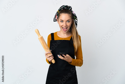 Young Lithuanian woman holding a rolling pin isolated on white background surprised and sending a message