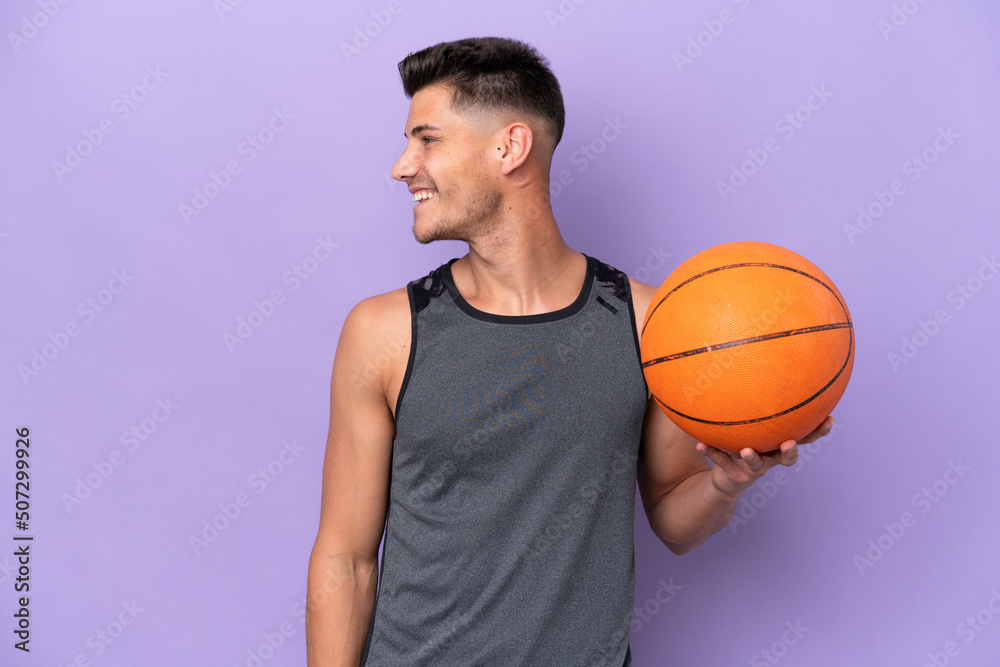 young caucasian woman  basketball player man isolated on purple background looking side
