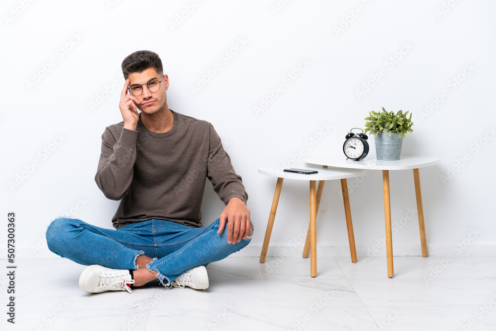 Young caucasian man sitting in his home isolated on white background thinking an idea Young caucasian man sitting in his home isolated on white background thinking an idea