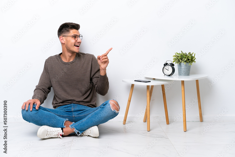 Young caucasian man sitting in his home isolated on white background intending to realizes the solution while lifting a finger up Young caucasian man sitting in his home isolated on white background intending to realizes the solution while lifting a finger up