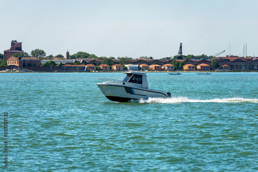 Obraz premium Small white speed boat moving in the Venetian lagoon to the Venice islands, the fastest way to travel in this city. Venice, Veneto, Europe.