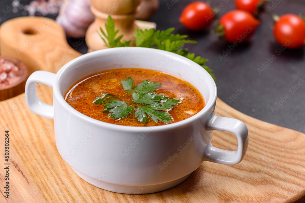 Fresh delicious tomato soup with spices and parsley in a white bowl on a wooden board Fresh delicious tomato soup with spices and parsley in a white bowl on a wooden board