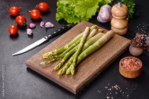 A bunch of branches of fresh green raw asparagus on a wooden cutting board