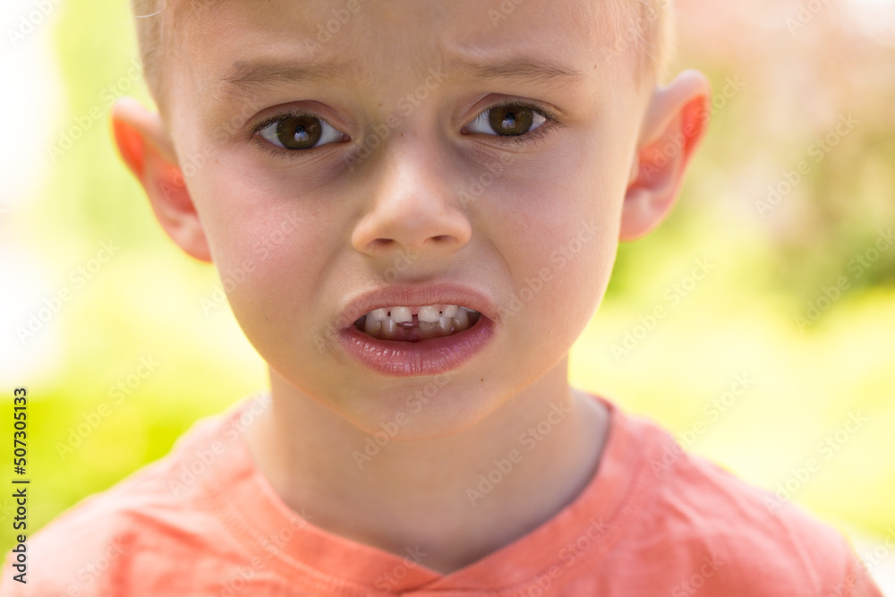 five-year-old boy making faces. A five-year-old blond boy makes faces while standing on the street in sunny weather