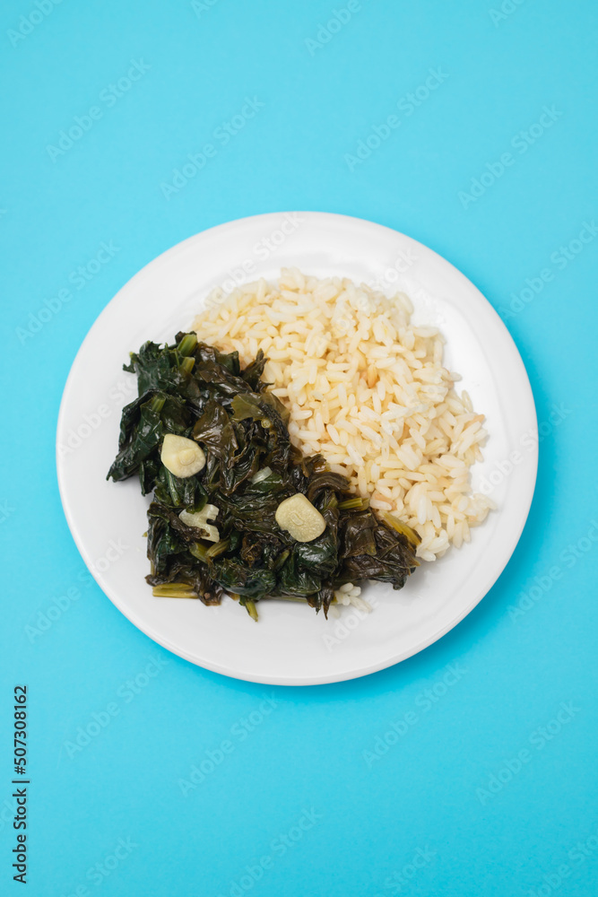fried spinach with garlic and boiled rice on plate fried spinach with garlic and boiled rice on plate
