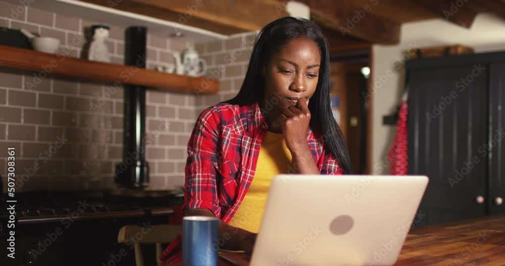 4k cheerful young African American woman working on her laptop while being seated at a table at home 4k cheerful young African American woman working on her laptop while being seated at a table at home