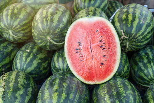 Watermelon cut in half to show its freshness on a stall with lots of watermelons.