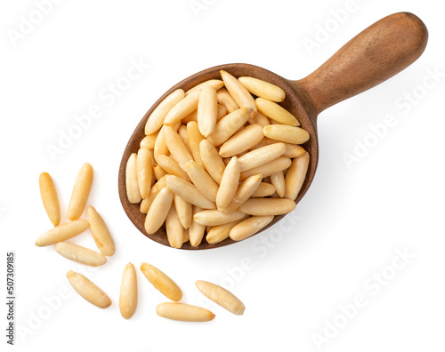 Roasted pine nuts in the wooden spoon, isolated on white background, top view.