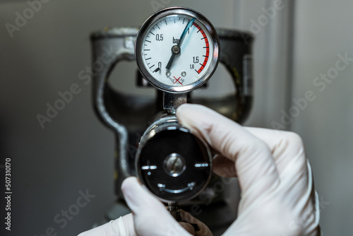Close up of a hand in gloves adjusting a barometer of a nitrogen cylinder or compressed air photo