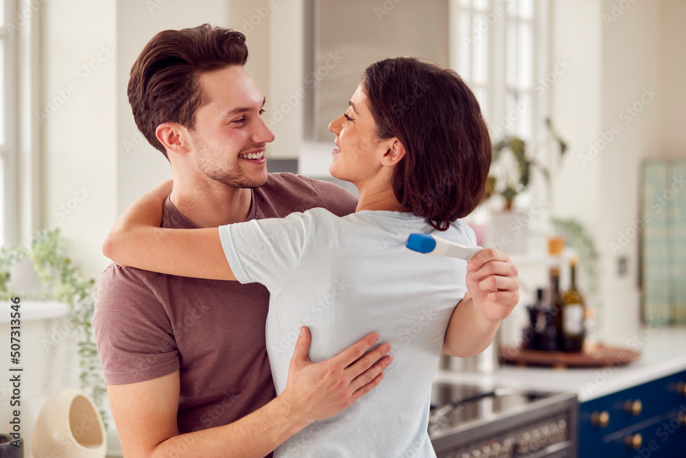 Happy Transgender Couple At Home In Kitchen Celebrating Positive Pregnancy Test Happy Transgender Couple At Home In Kitchen Celebrating Positive Pregnancy Test