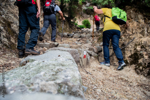 Gruppo di escursionisti di trekking lungo un sentiero di terra battuta e rocce in montagna