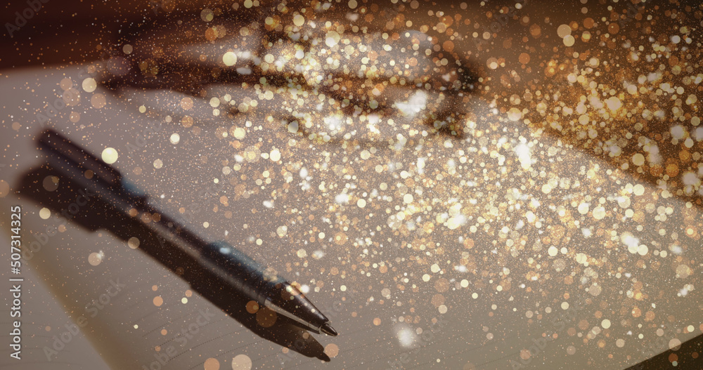 Image of sparkles over notepad and pen