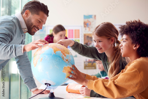 Group Of Multi-Cultural Students With Teachers In Classroom Looking At Globe In Geography Lesson photo