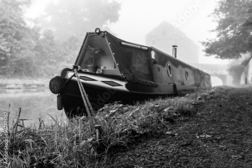 Stampa su tela Moored narrow boat in the mist seen in monochrome.