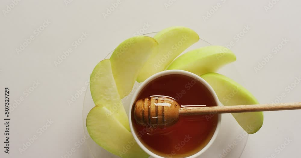 Video of honey in jar and apple slices lying on white surface