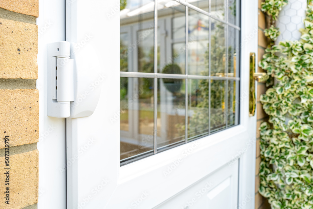 Shallow focus of door hinges seen on a newly installed double glazed PVC door which leads to a kitchen. Seen with installed leaded windows. Shallow focus of door hinges seen on a newly installed double glazed PVC door which leads to a kitchen. Seen with installed leaded windows.