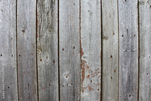 Old dry gray wooden fence with weathered vertical boards is a vintage background texture.