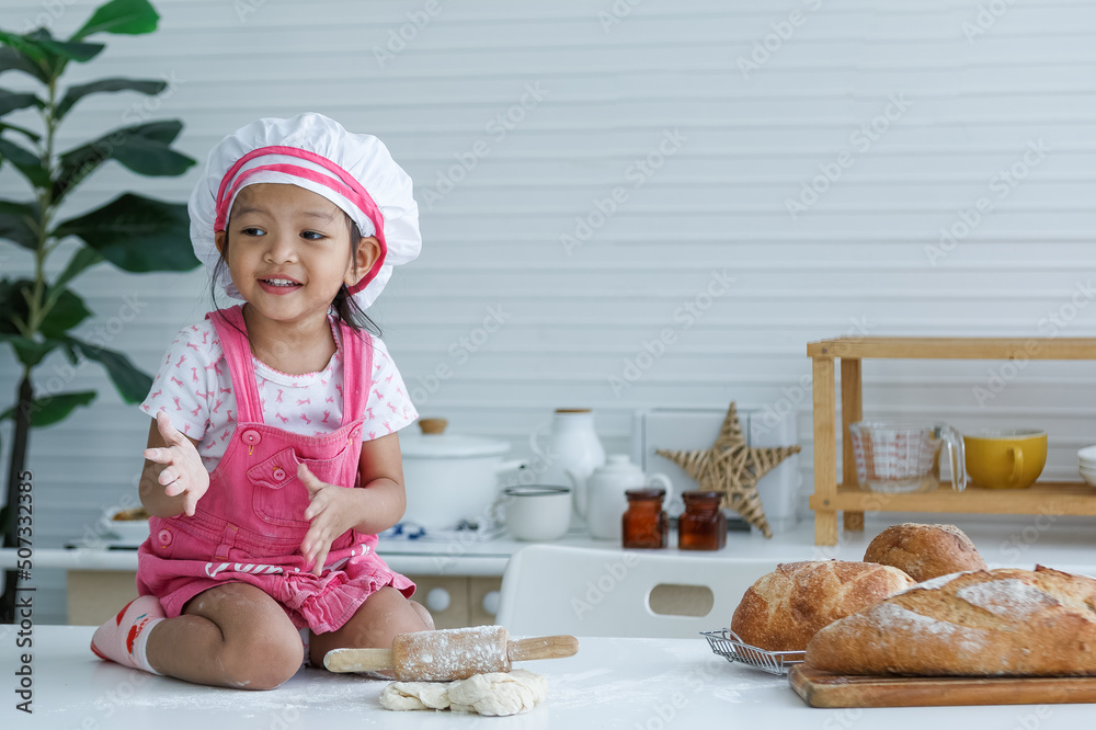 Cute little chef sitting on the table learning to make bread Cute little chef sitting on the table learning to make bread