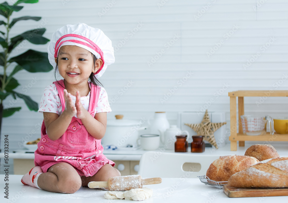 Cute little chef sitting on the table learning to make bread Cute little chef sitting on the table learning to make bread