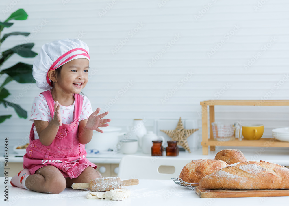 Cute little chef sitting on the table learning to make bread Cute little chef sitting on the table learning to make bread