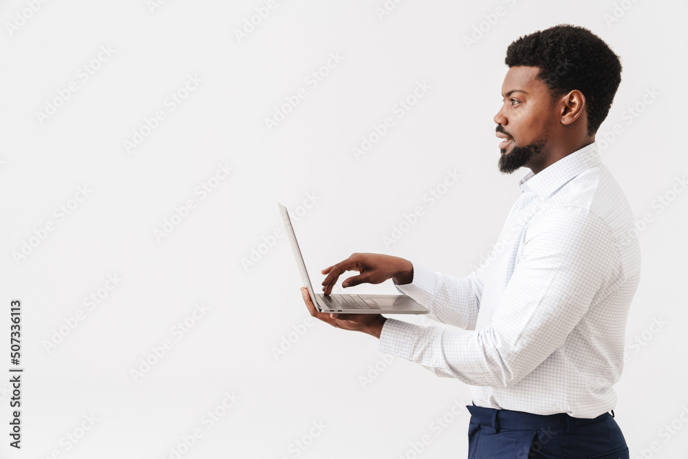 Black bearded man wearing shirt working with laptop