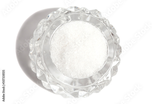 Salt in a glass crystal bowl. Salts top view. Sea salted isolated on a white background.