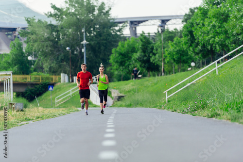 Young running couple jogging on an asphalt road in the park © qunica.com