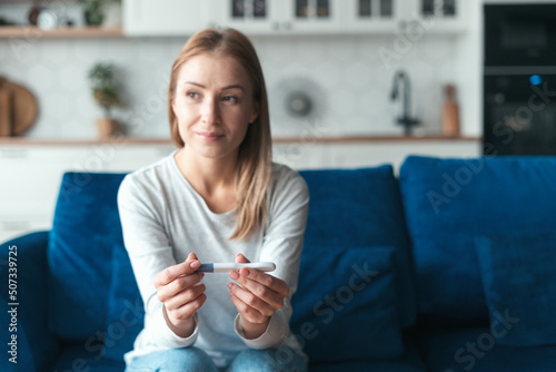 Thoughtful woman holding test when sitting on sofa photo